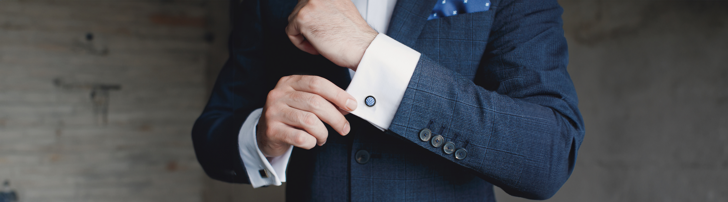 A man in a navy blue suit adjusts his cufflinks. Text on the image reads "For Men.