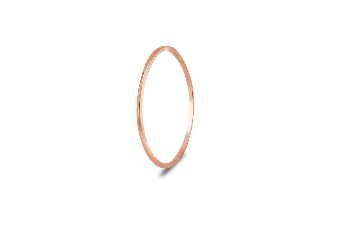 The Cosmic Boulevard Cosmic Thread 9ct Gold Stacking Ring features a thin, polished band in rose gold, displayed on a plain white background with a subtle shadow—a delicate handmade jewellery piece from Dublin.