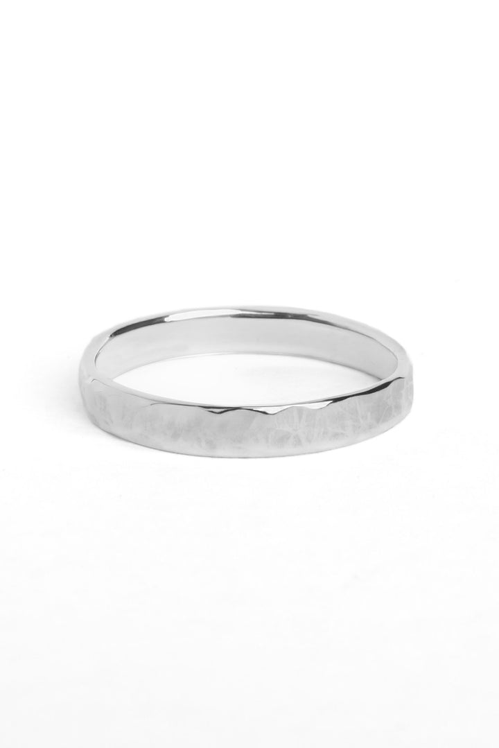 A flat sterling silver ring 4mm wide with a textured finish on the outside of the band.