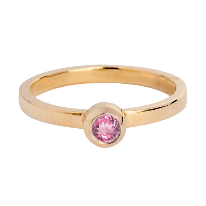 9ct yellow gold ring with a small pink spinnell in a bezel setting. The band is flat in shape and is 2mm wide. The stone is 3mm in diameter.