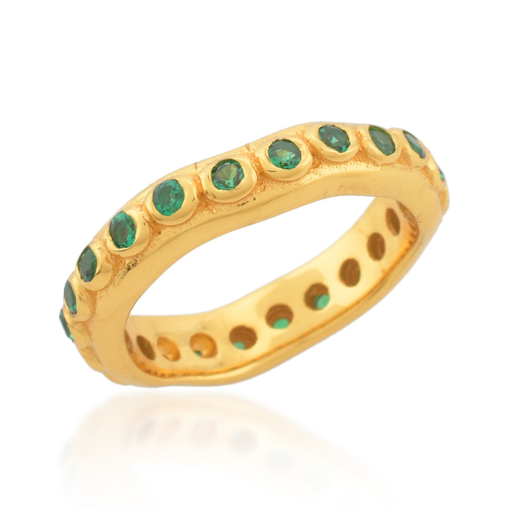 A Shyla Astri Stacking Ring featuring a continuous row of small, round, green emerald stones set into the band. Crafted from 22 carat gold with a textured finish, this hypoallergenic piece is both luxurious and eye-catching. Perfect for pairing with other Astri stacking rings.