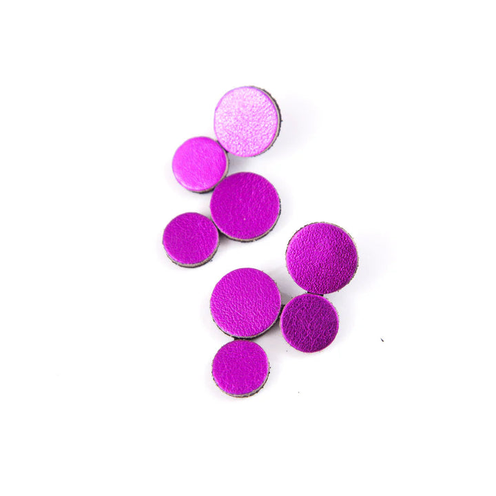 Eight round, textured Abstraction Pink Earrings by Iskin Sisters in various purple and pink shades are arranged on a white background.