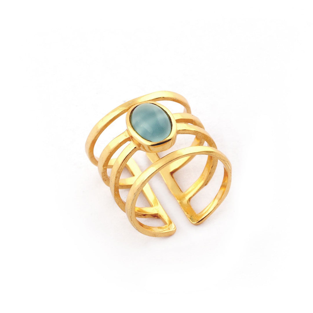 The Andi Banded Ring in Amazonite by Watermelon Tropical features an oval-shaped amazonite gemstone at the center. This exquisite piece showcases an open-band design with multiple parallel bands that converge at the stone, creating a modern and stylish appearance. Available in gold, silver, and black variants, the ring is photographed against a plain white background for a clean look.