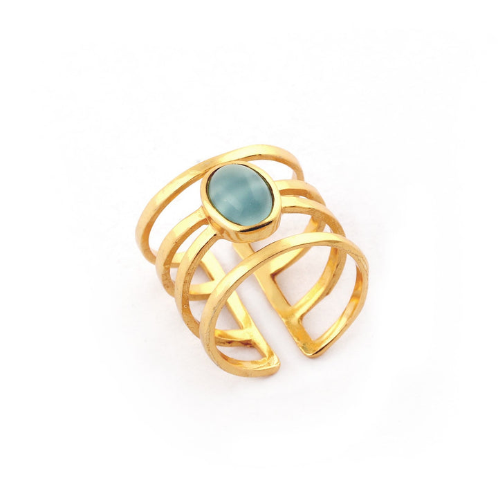 The Andi Banded Ring in Amazonite by Watermelon Tropical features an oval-shaped amazonite gemstone at the center. This exquisite piece showcases an open-band design with multiple parallel bands that converge at the stone, creating a modern and stylish appearance. Available in gold, silver, and black variants, the ring is photographed against a plain white background for a clean look.