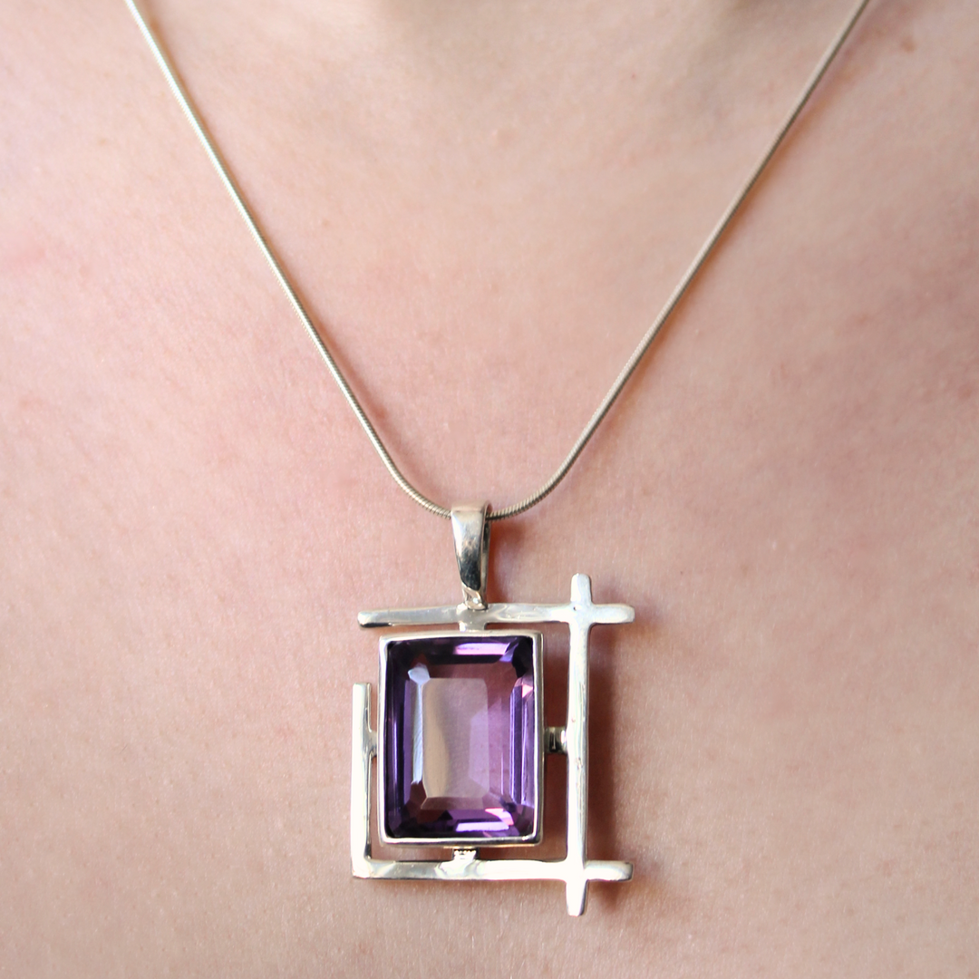 A close-up of the Gallardo & Blaine Designs Art Deco Pendant, featuring a modern geometric design and a square purple gemstone, worn as a sterling silver necklace.