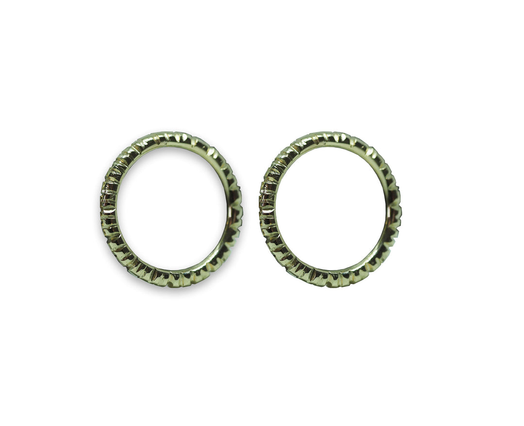 Two close-up views of identical wheel-like objects featuring a circular shape with ridged, gear-like edges. Resembling exquisitely crafted golden earrings, the Into The Light Circle Earrings 9ct Yellow Gold by Aud are positioned side by side against a plain white background, showcasing their hand-engraved details in yellow gold.
