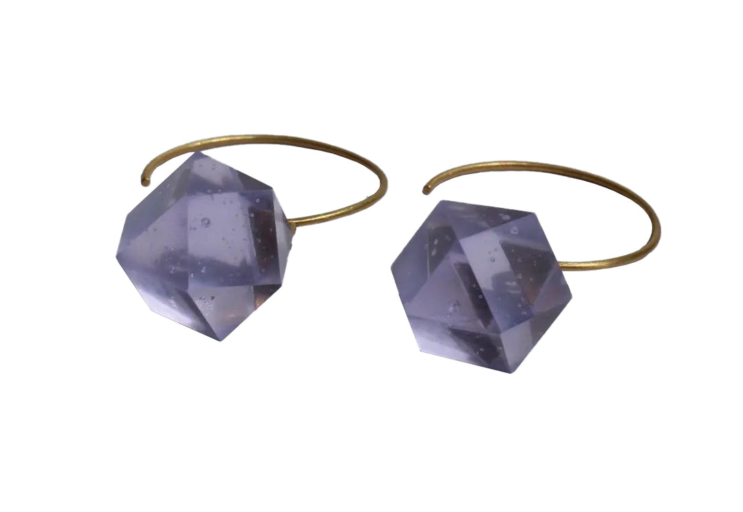 The Beira by Irene Reyes GEO Round Hook Earrings showcase two gold-colored hoops adorned with angular faceted translucent gray bullseye glass crystals, each featuring multiple reflective surfaces for an elegant touch.