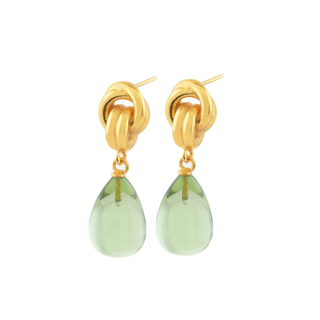 Introducing the Chunky Knot Earrings from Shyla, featuring a stylish pair of high-shine gold knotted drop earrings adorned with dangling teardrop-shaped green gemstones. The chunky knot forms the post, with the elegant green gemstones hanging directly below. These sophisticated earrings not only offer a chic and fashionable design but are also hypoallergenic, making them perfect for sensitive ears.