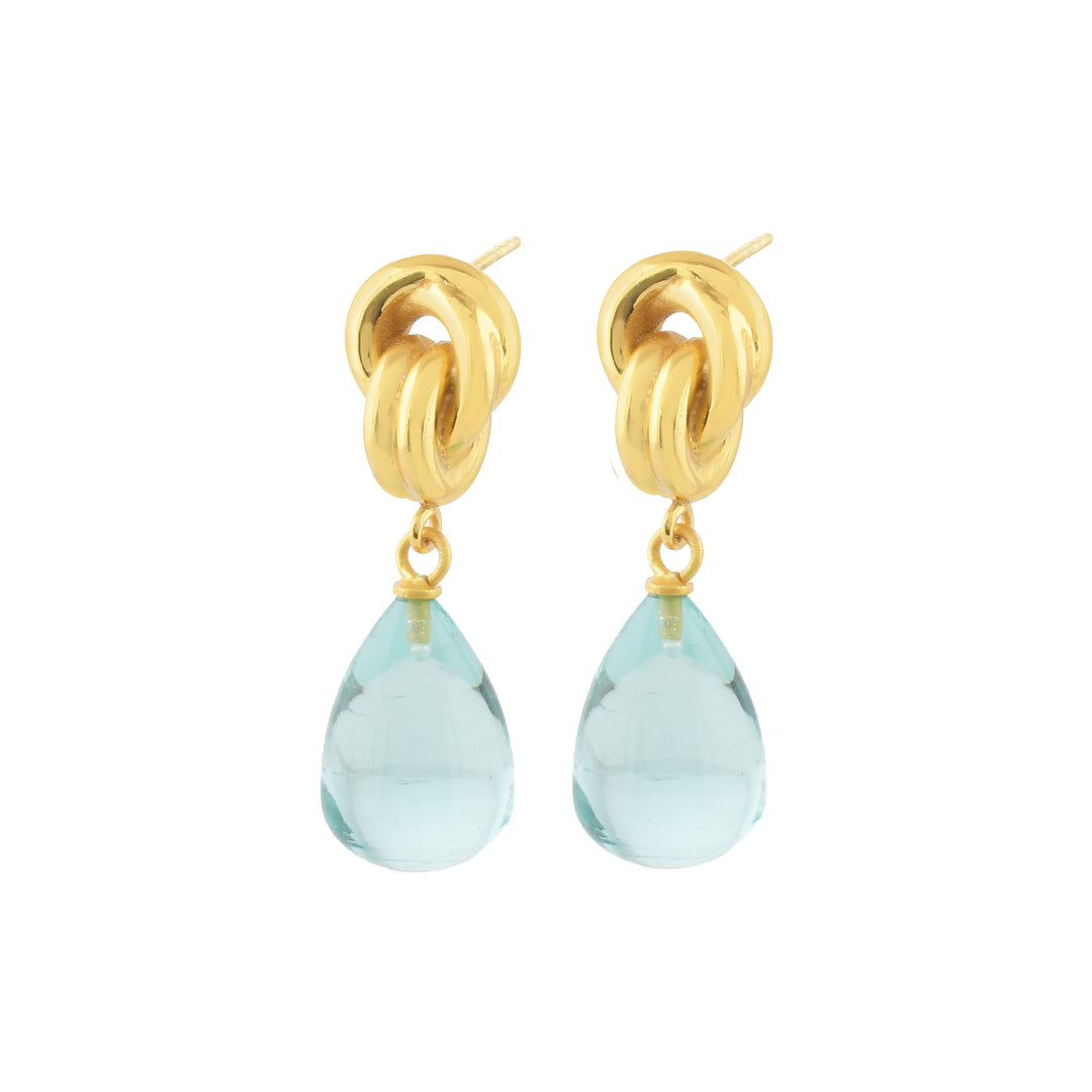 Shyla's Chunky Knot Earrings in various colours feature intertwined gold loops with a dangling teardrop-shaped light blue gemstone, crafted as hypoallergenic jewellery and shown on a white background.