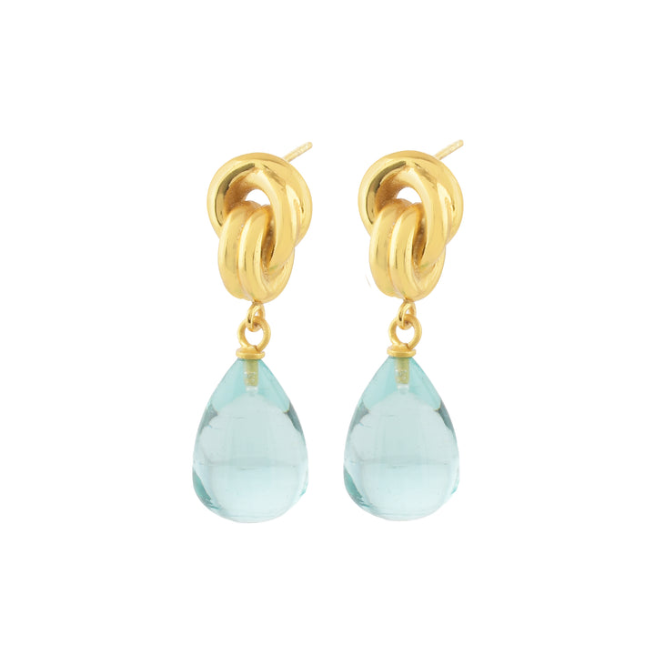 Shyla's Chunky Knot Earrings in various colours feature intertwined gold loops with a dangling teardrop-shaped light blue gemstone, crafted as hypoallergenic jewellery and shown on a white background.