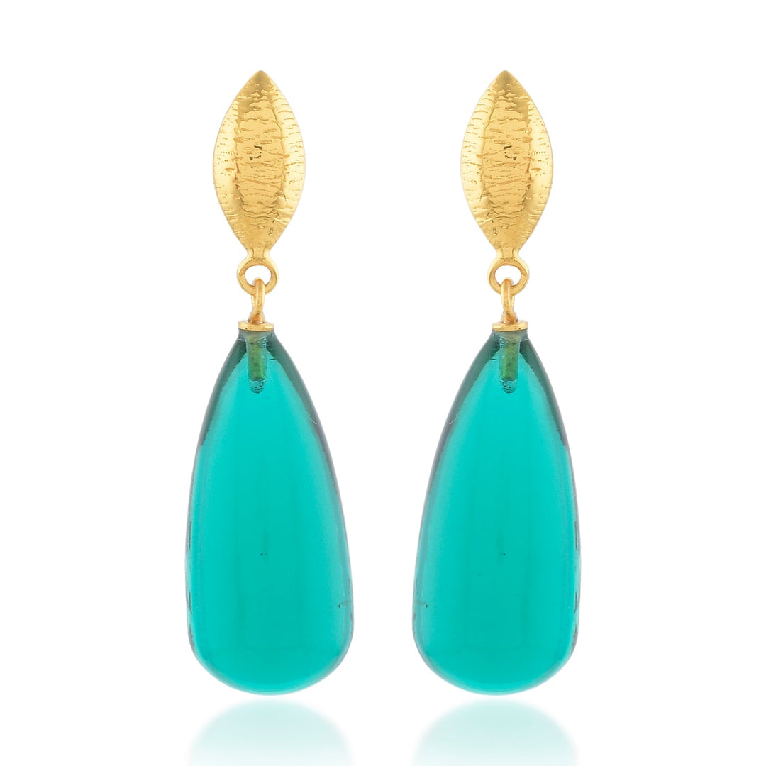 The Corine Earrings by Shyla are a pair of elegant, hypoallergenic drop earrings featuring gold, leaf-shaped studs at the top and elongated, teardrop-shaped turquoise stones dangling below. The smooth and glossy turquoise stones add a vibrant pop of color to this exquisite design.