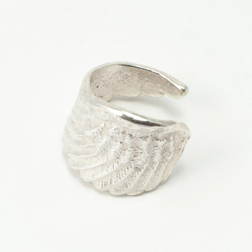 The Angel Wing Ring by Jennifer Kinnear is an open sterling silver ring with a textured feather-like design, shown on a white background. Available in silver or gold.