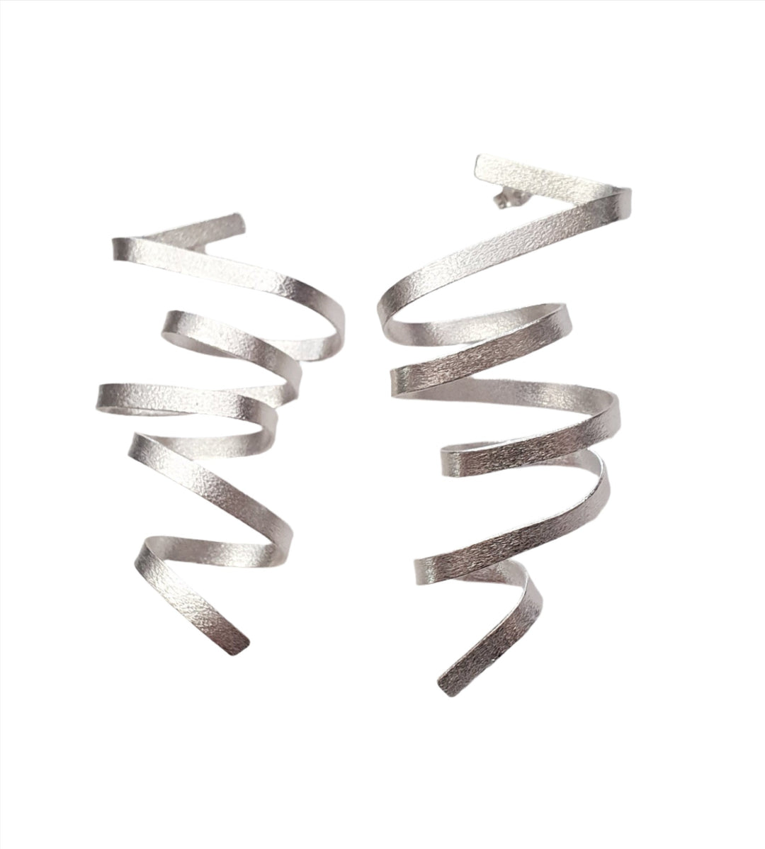 A close-up of the Concertina Statement Silver Earrings by Georgia Charal, showcasing their textured surface against a white background. The sterling silver earrings are unwound to create a coiled spring effect. The simple yet elegant design features multiple loops in each lightweight earring.