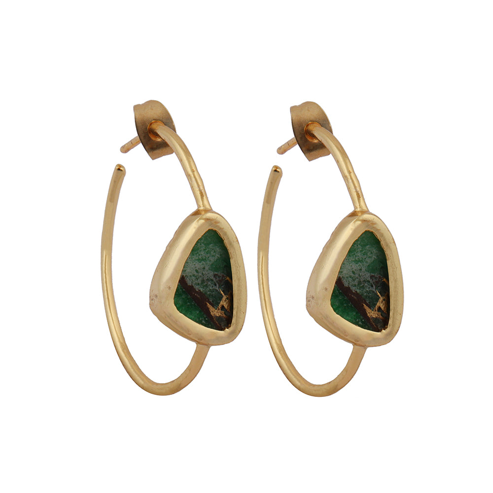 The Elena Gold & Green Turquoise Hoop Earrings from Watermelon Tropical feature gold hoops with triangular green Turquoise stones at the center. The rustic appearance and dark striations of the stones enhance their natural beauty, while sterling silver prongs delicately secure them. These earrings boast a minimalist, elegant design that combines gold and black accents gracefully.