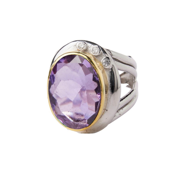 The Eyetelia Ring by Gallardo & Blaine Designs features a large oval-cut purple gemstone in sterling silver gold vermeil, accented with three small round diamonds on one side for an elegant statement look.
