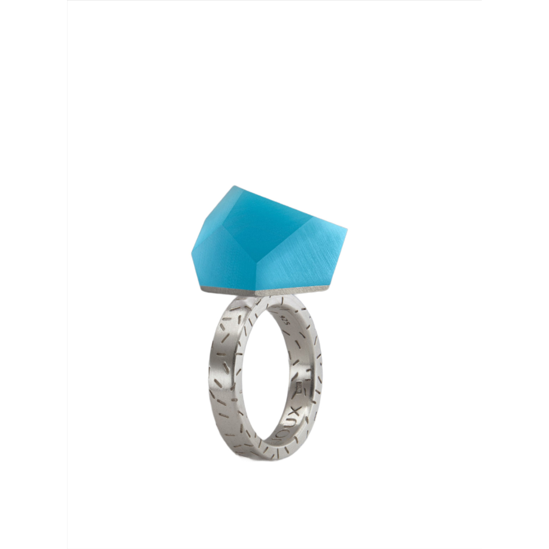 The Fruit Bijoux Ring Top VU Crystals Capri Blue by Fruit Bijoux is a sterling silver ring featuring engraved details and a bold, faceted geometric blue stone, shown on a plain white background.