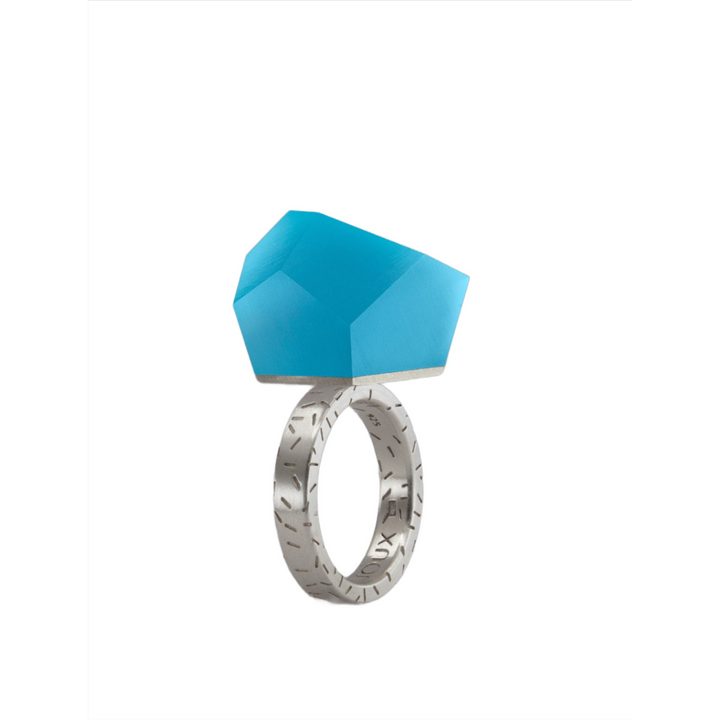 The Fruit Bijoux Ring Top VU Crystals Capri Blue by Fruit Bijoux features a faceted geometric blue crystal set on a textured sterling silver band, showcased against a plain white background.