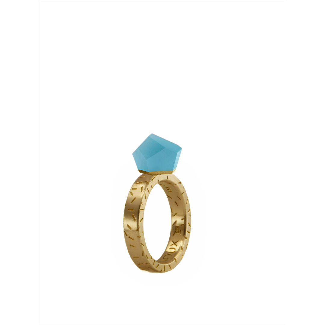 The Fruit Bijoux Ring Top VU Crystals Capri Blue by Fruit Bijoux features a large, angular blue gemstone on a 24ct gold-plated ring with engraved details, shown against a plain white background.