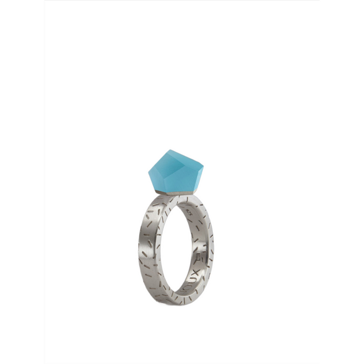 The Fruit Bijoux Ring Top VU Crystals Capri Blue by Fruit Bijoux features engraved sterling silver and a faceted geometric blue gemstone, showcased against a white background.