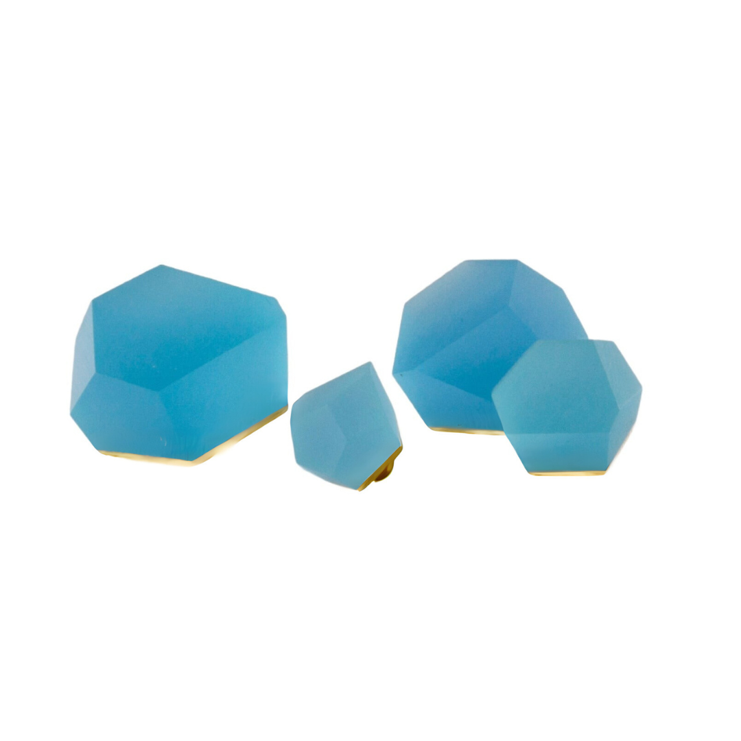Four faceted Fruit Bijoux Ring Top VU Crystals Capri Blue by Fruit Bijoux, in geometric shapes and various sizes of light blue, each featuring a flat 24ct gold-plated base, displayed on a white background.
