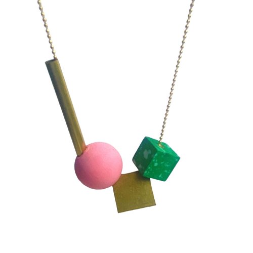 The Geo Necklace in Pink & Green by Shock of Grey features a gold-plated chain with four geometric FSC-certified wooden beads in playful shapes and colors, creating a fun, abstract look.