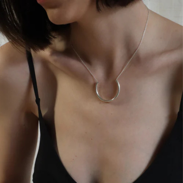 A woman models Inó Jewellery's Half Chain Necklace and a black spaghetti strap top, shown from shoulders to chest, as she turns her head slightly left.