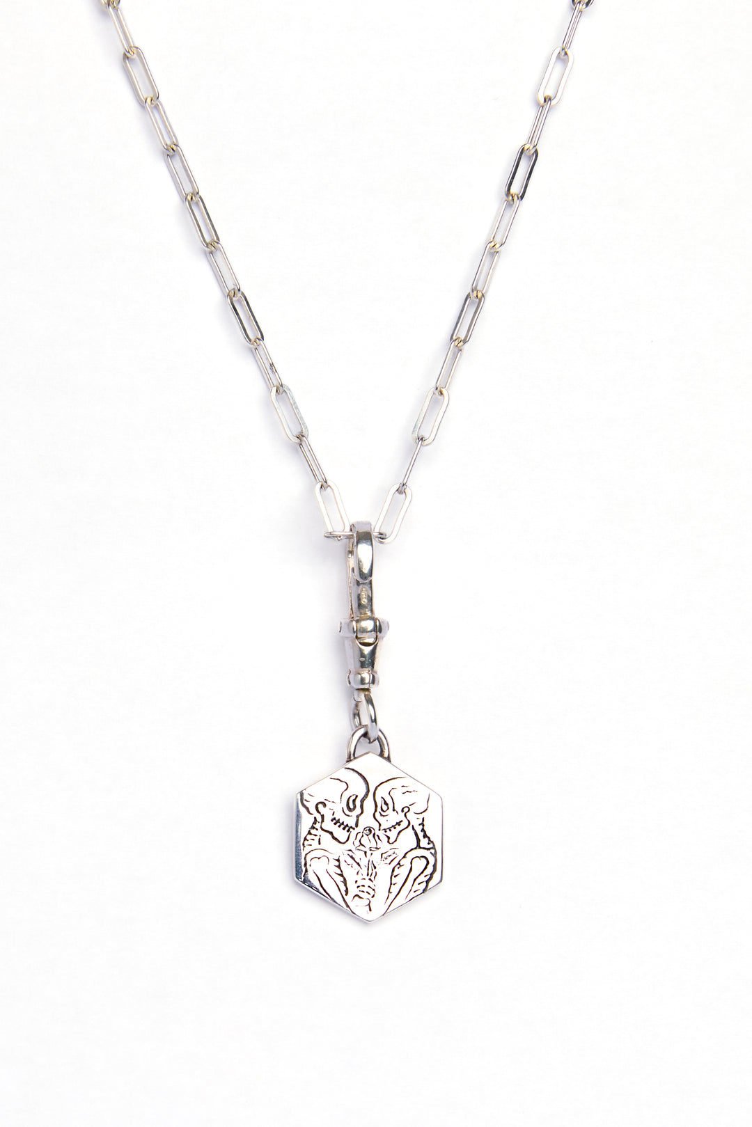 The Lovers Silver Pendant by Cosmic Boulevard features a rectangular chain and geometric pendant engraved with an abstract animal face, captured on a white background—a modern, subtle symbol of love.