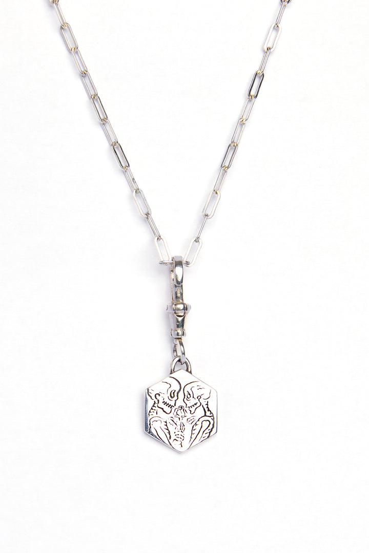 The Lovers Silver Pendant by Cosmic Boulevard features a rectangular chain and geometric pendant engraved with an abstract animal face, captured on a white background—a modern, subtle symbol of love.