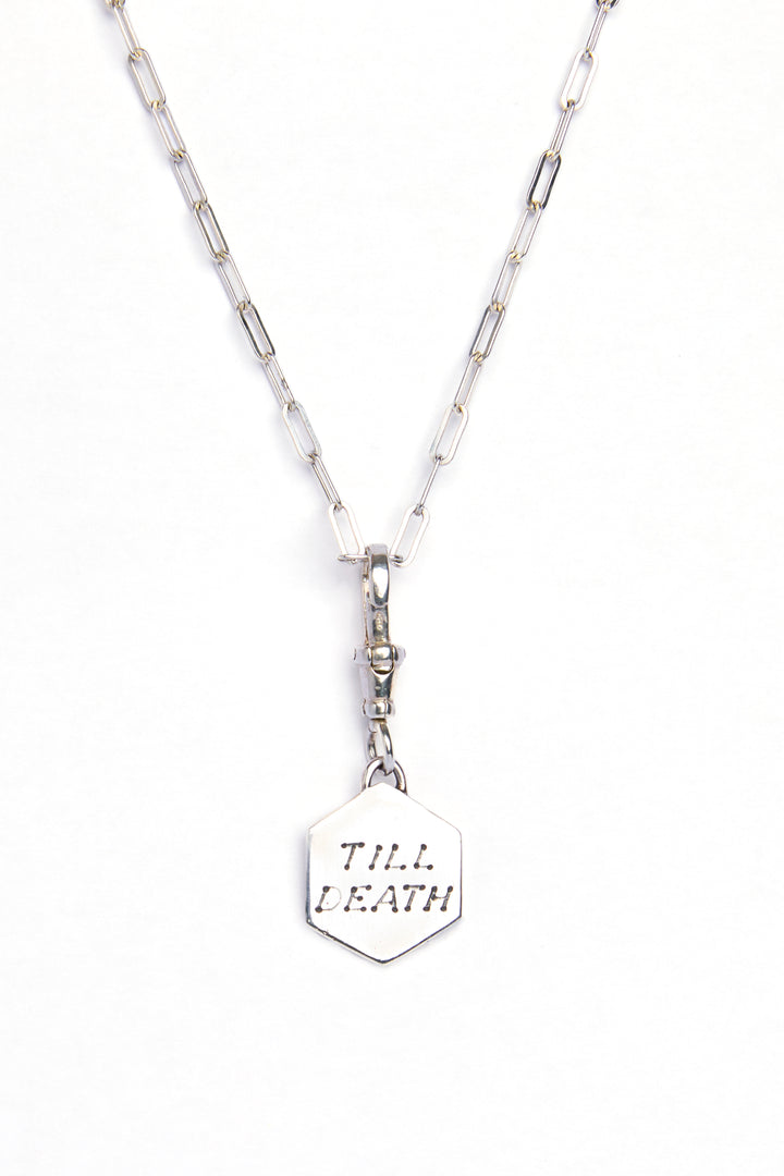 The Lovers Silver Pendant by Cosmic Boulevard features a hexagonal sterling silver pendant engraved with "TILL DEATH," hanging from a silver chain and displayed against a white background.
