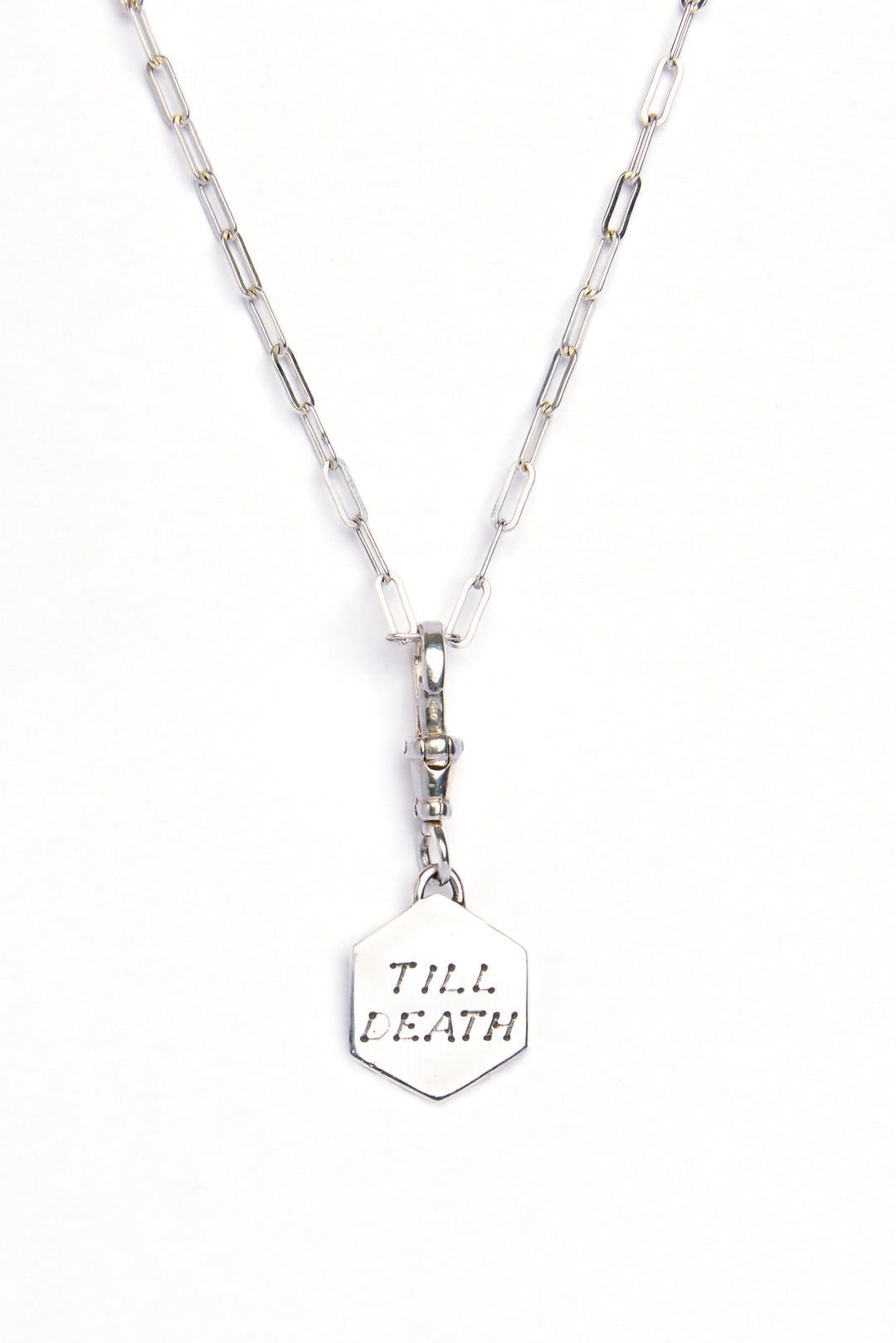 The Lovers Silver Pendant by Cosmic Boulevard: a sterling silver hexagonal pendant engraved with "TILL DEATH," hanging from an elongated-link silver chain—symbolizing everlasting love.