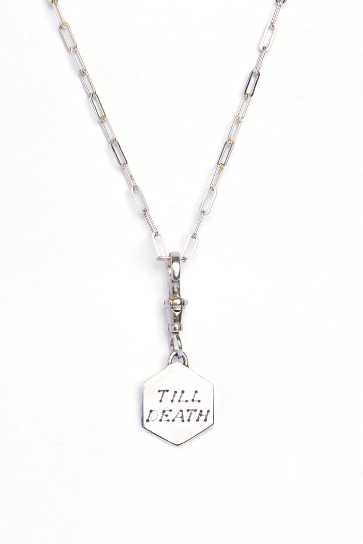 The Lovers Silver Pendant by Cosmic Boulevard: a sterling silver hexagonal pendant engraved with "TILL DEATH," hanging from an elongated-link silver chain—symbolizing everlasting love.