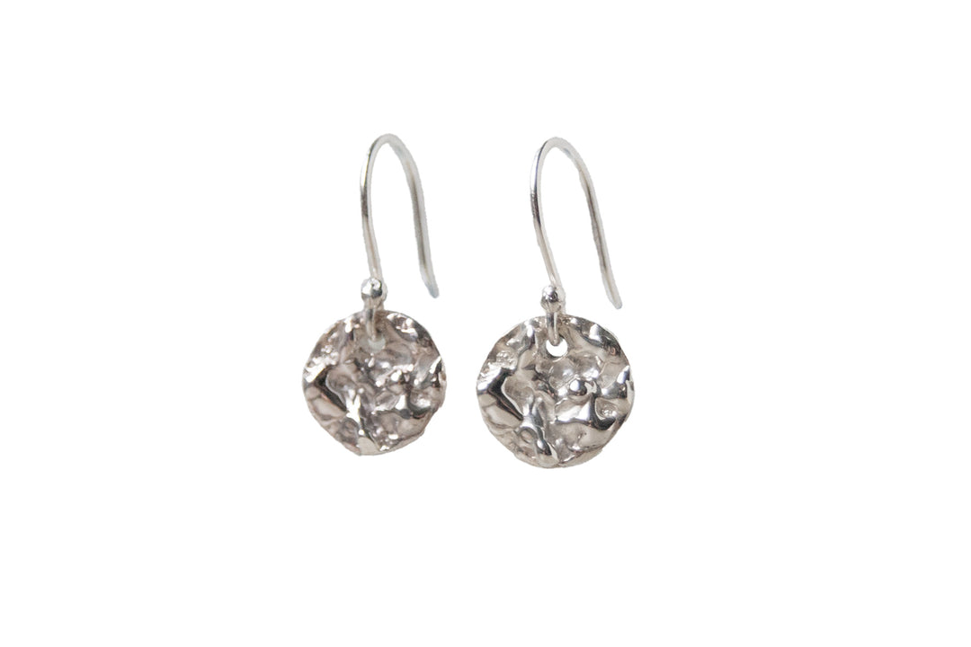 Molten Moonscapes Silver Drop Earrings by Ava Jane Jewellery feature handmade sterling silver, hammered round discs on simple hooks—an elegant, unique gift for any occasion. Displayed on a white background.