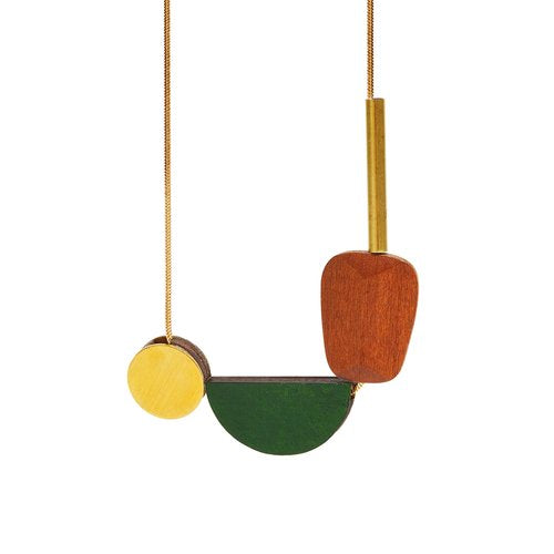 The Multishape Plus Necklace in Emerald Green by Shock of Grey features laser-cut, FSC-certified birchwood beads—a yellow circle, green half-circle, and reddish-brown shape—on a gold chain. Handcrafted in Dublin.