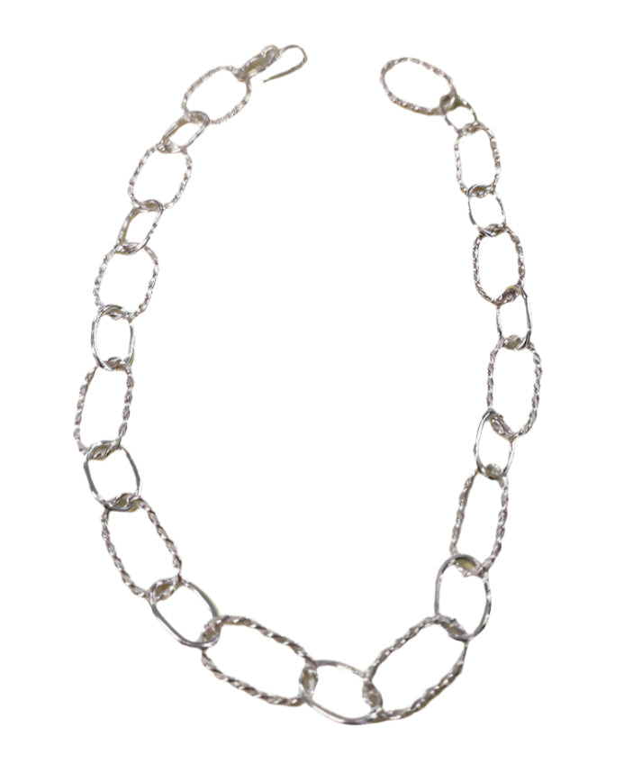 The Raw Chain Necklace by Inó Jewellery features large, textured oval sterling silver links and a simple hook clasp. Displayed on a white background, it can also be styled as an adjustable choker for added versatility.