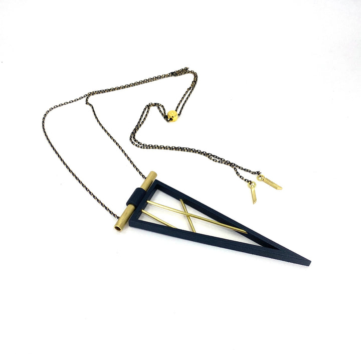 The Elsiem Rapture Spear Long Chain Necklace features a modern triangular black SLS nylon pendant, accented with gold rods and a gold tube, all hanging from a delicate, adjustable gold chain.
