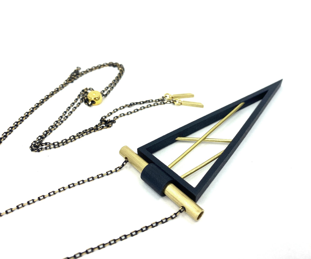 The Elsiem Rapture Spear Long Chain Necklace is a modern neckpiece featuring a black triangular pendant with gold accents on a dark chain and gold clasp, shown against a white background.
