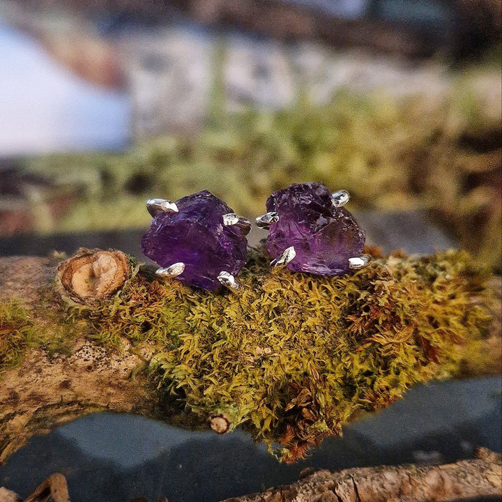 Raw purple amethyst stud earrings with silver claw setting.