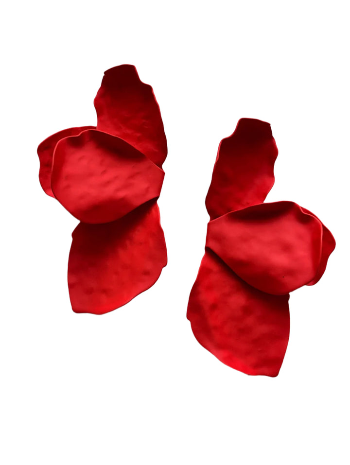 The Bougainvillea Earrings by Kybalion Jewellery feature two red, abstract petal-like shapes that contrast beautifully against a speckled white and gray surface. These handmade pieces come with durable stainless steel posts for a striking visual effect.