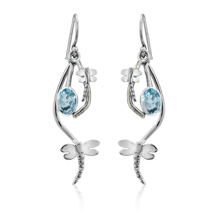 Ripple Earrings by Gallardo & Blaine Designs feature dragonfly-shaped sterling silver with light blue oval gemstones at the center. These elegant earrings have a polished finish and dangle from hooks.