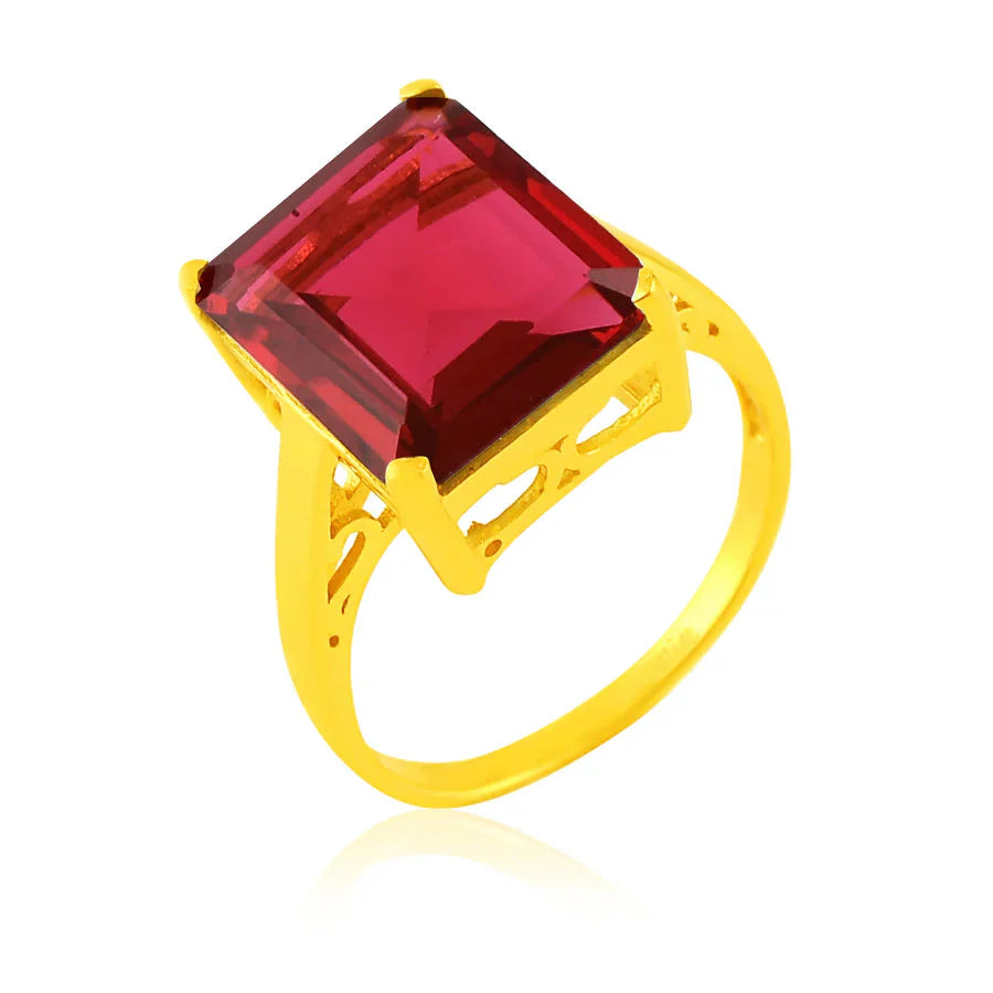 The Claudia Ring by Shyla is a vintage-inspired gold chunky ring featuring a large, square-cut red gemstone in a raised prong setting, accented with decorative cut-out details along the band.