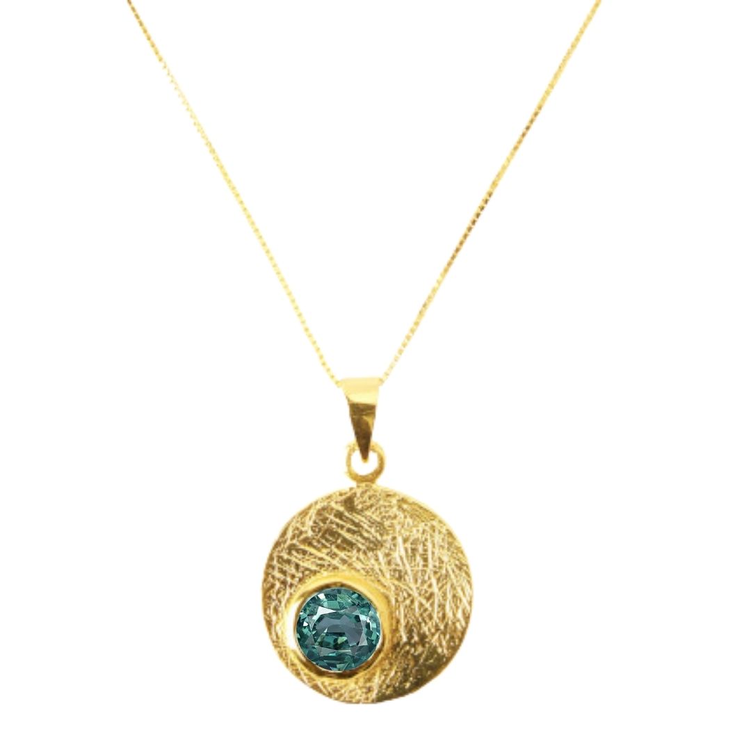 The Selene Necklace Gold - Small by Gallardo & Blaine Designs features a gold-plated fine chain with a textured round pendant and blue-green gemstone, available in various gemstones.