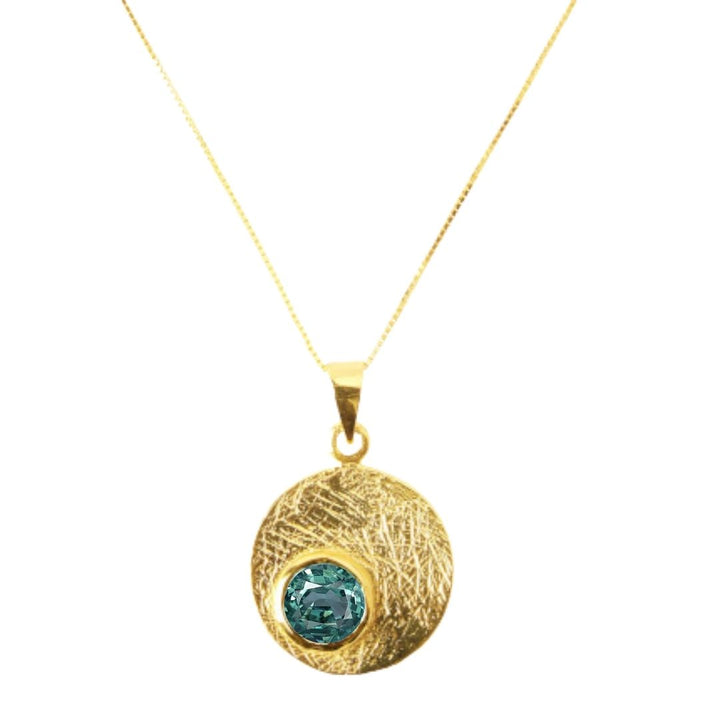 The Selene Necklace Gold - Small by Gallardo & Blaine Designs features a gold-plated fine chain with a textured round pendant and blue-green gemstone, available in various gemstones.