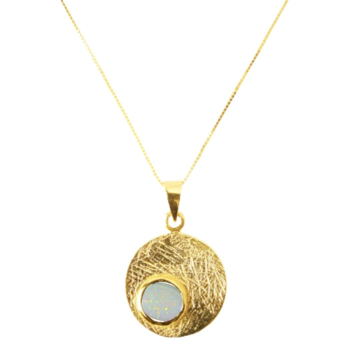 The Selene Necklace Gold - Small by Gallardo & Blaine Designs features a round textured pendant with a light blue opal gemstone, suspended from a delicate gold-plated chain.