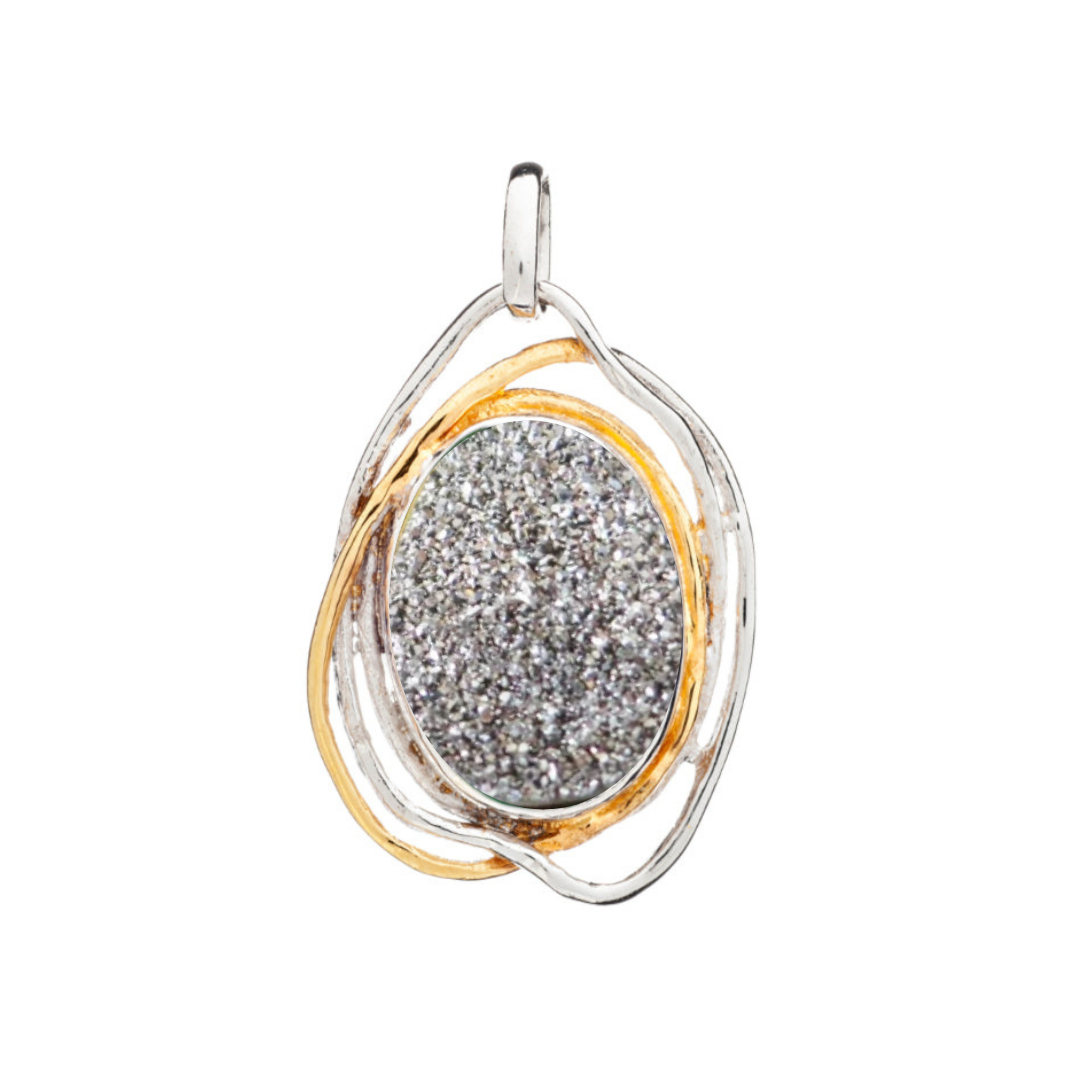 The Cosmos Pendant Large by Gallardo & Blaine Designs is a captivating statement piece, featuring an oval gemstone nestled in an intertwined silver and gold frame. Its minimalist, elegant design makes it a timeless accessory.