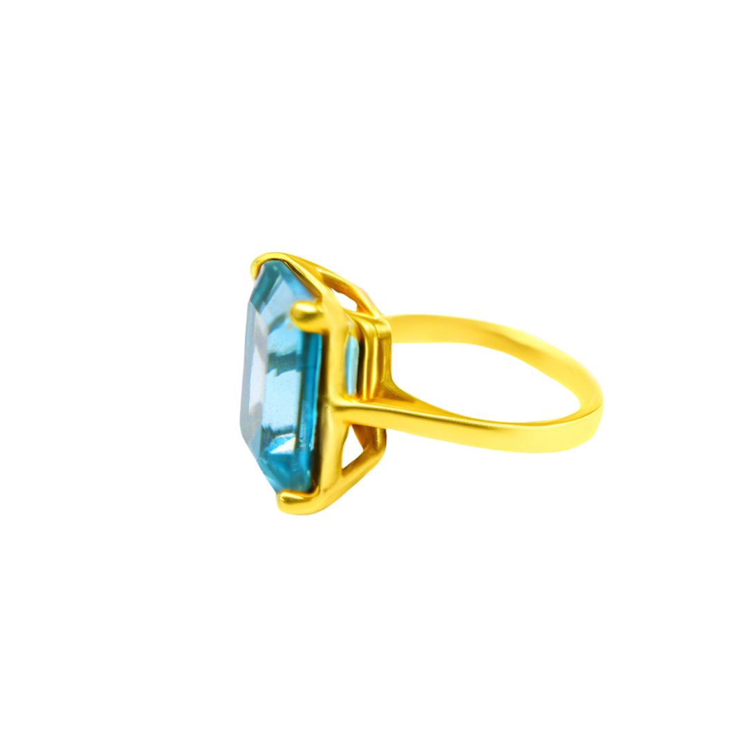The Stellar Ring in Hydro Blue Topaz by Gallardo & Blaine Designs features a large, rectangular blue stone in a prong setting, displayed from the side on a white background.