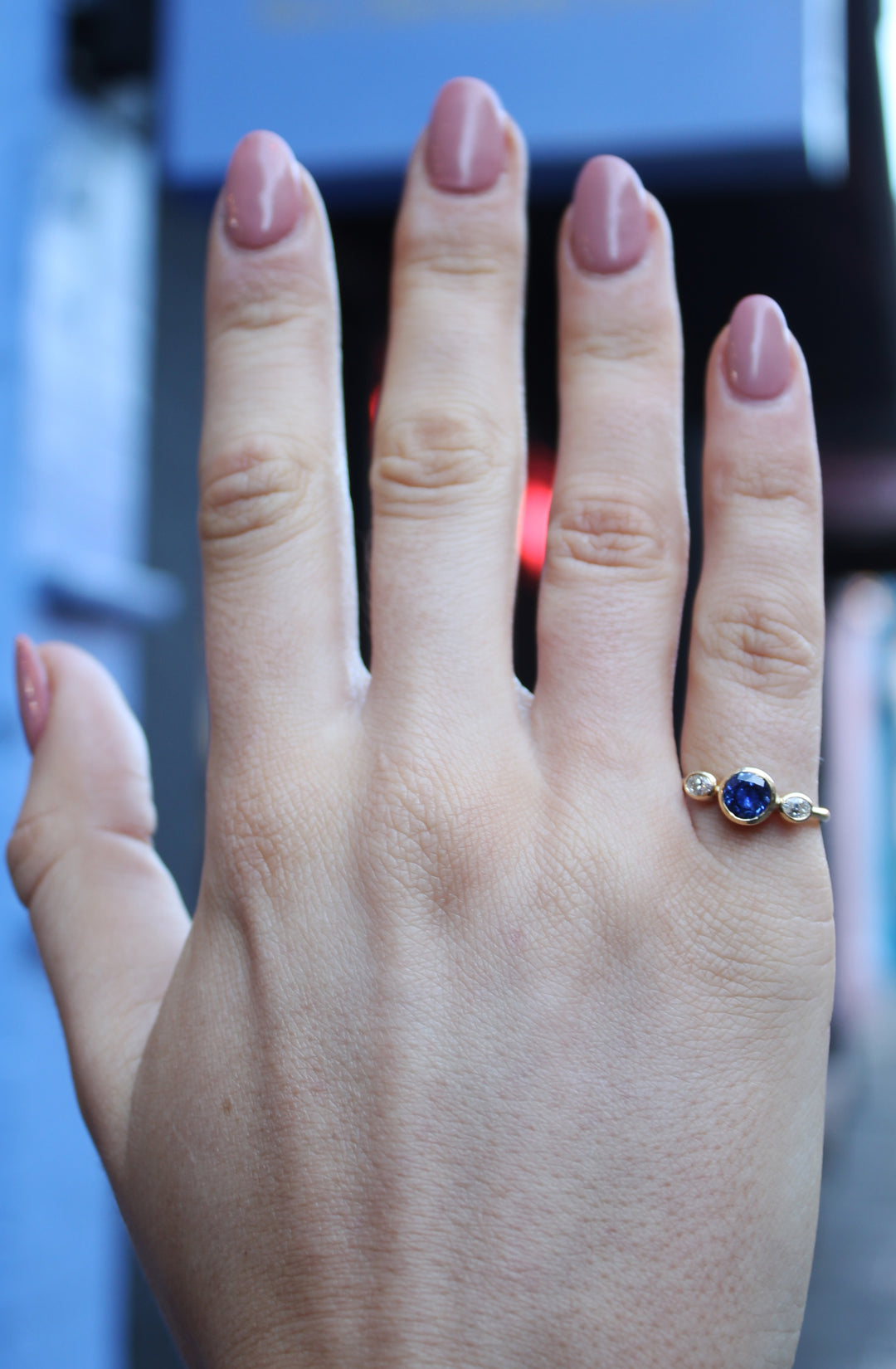 18ct yellow gold ring with round sapphire in the centre and an oval shaped diamond on either side. The band is tapered to a D shape, the band is widest at the back at 2.3mm and becomes thinner towards the front of the ring.
