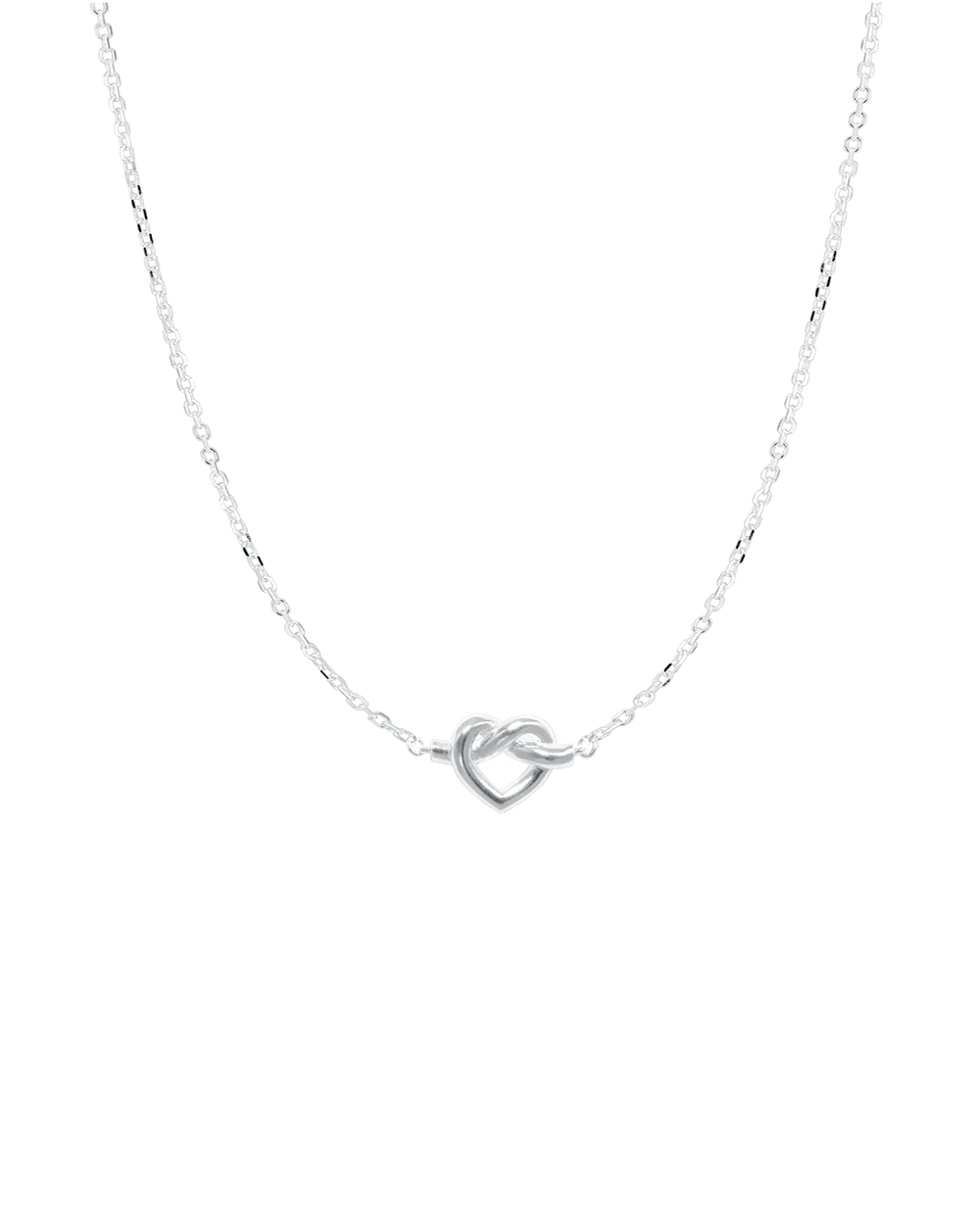 The Tied Heart Necklace by Jane Koenig is a delicate sterling silver piece with a small heart-shaped pendant on an adjustable fine chain, showcasing minimalist elegance against a plain white background.