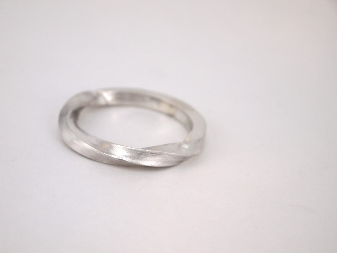 The Torn Silver Ring by MarCucurella is a minimalist handmade piece with a subtle twist design, displayed on a plain white background.
