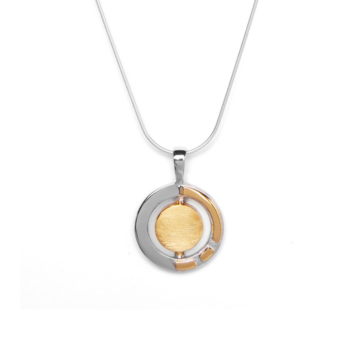 The Urú Small Pendant & Chain by Gallardo & Blaine Designs features a round sterling silver pendant with a brushed gold-toned center, shiny silver outer ring, and gold accents inspired by classic Irish jewelry.