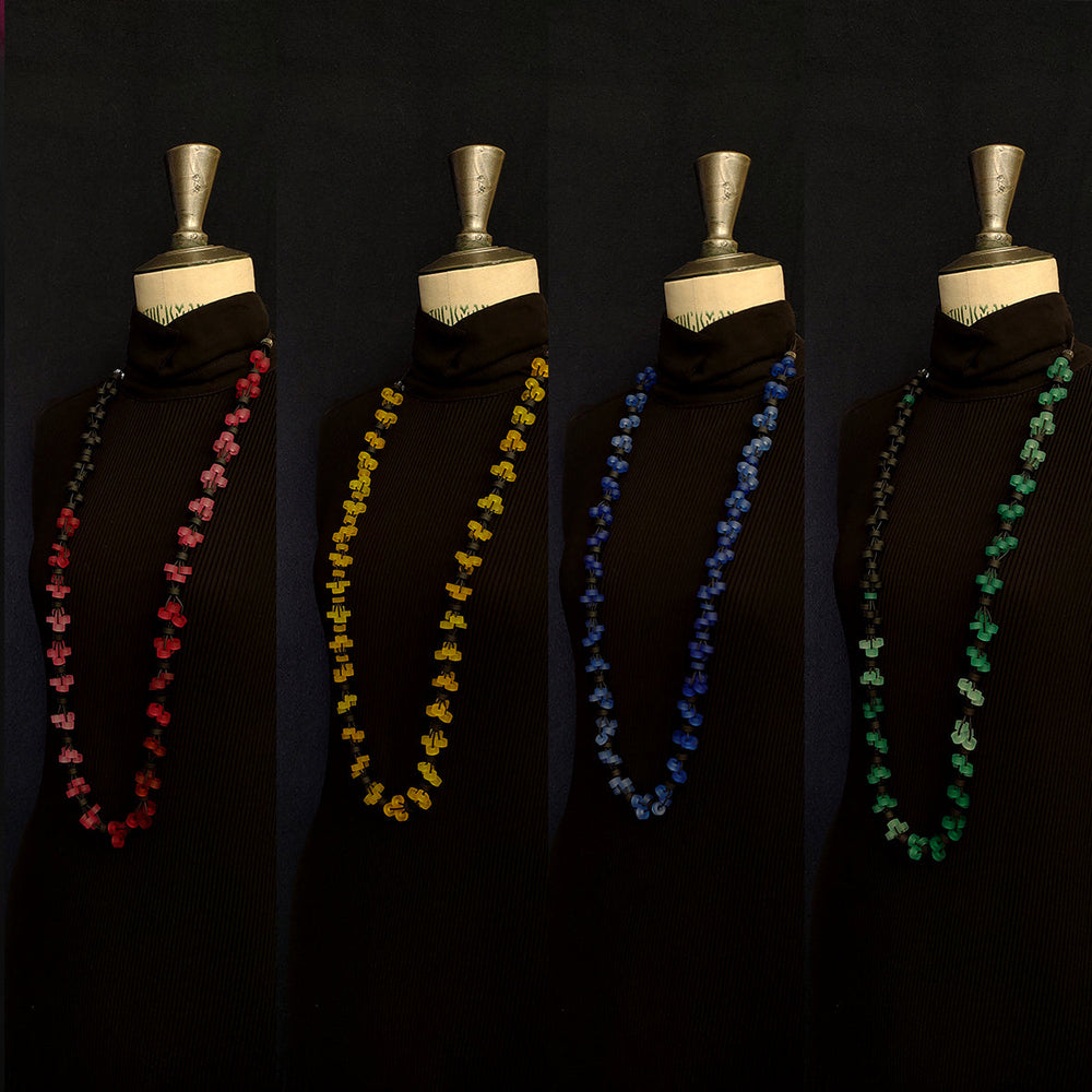 A mannequin wearing a black turtleneck is adorned with four differently colored Verona Long Necklaces by Alex + Svet: red, yellow, blue, and green, displayed side by side. These hypoallergenic necklaces, handcrafted in Paris, are arranged vertically and hang down elegantly on the mannequin.